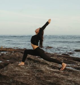 Frau macht Yoga am Meer als achtsame Bewegung für mehr Ruhe im Alltag