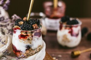 Protein Joghurt mit Beeren und Nussmus im Glas als sättigender Snack