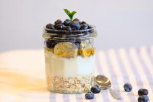 Haferbrei im Glas mit Beeren und Banane als gesunder Snack