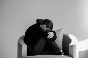 Frau sitzt zusammengesunken im Sessel – Symbol für mentale Überforderung, Stress und Gedankenchaos im Alltag